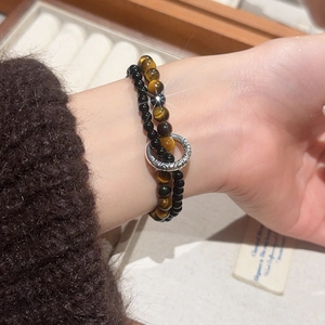 Detail of vintage tiger eye and pearl double-layer bracelet worn on a female wrist