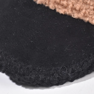 Close-up of warm sheepskin baseball cap with black wool felt and fluffy curly fleece texture