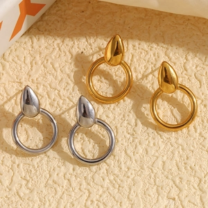 Minimalist 18K gold and silver teardrop ring earrings on a textured beige surface