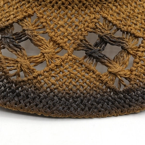 Macro shot of dark gradient hand-woven straw hat showing detailed hollow mesh texture