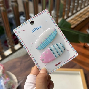 Détail de pinces à cheveux en acrylique à carreaux bleus et rayures roses avec texte Lovely