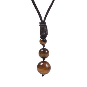 Detail of three tiger eye beads on a brown braided cord necklace against white backdrop