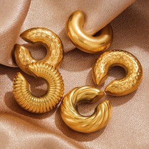 Detailed macro view of 5-piece gold-plated titanium steel twist ear cuffs on silk fabric