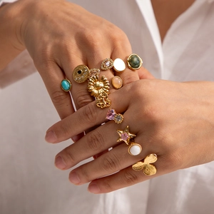 Close-up of bohemian gold ring set with sun, star, and evil eye motifs on model's fingers