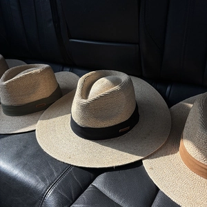 Detail of wide brim raffia straw hats with handmade metal tags on colored bands