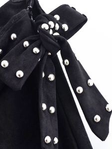 Detailed view of black fabric pants with decorative bow and silver stud embellishments
