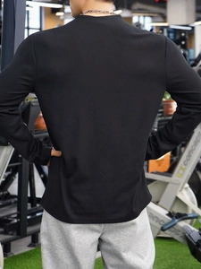 Rear view of men's slim fit black ribbed sports polo shirt in a gym setting