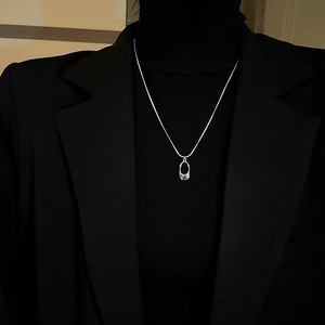 Macro detail of silver geometric hollow necklace with blue gem on black sweater