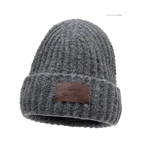 Close-up of gray chunky knit winter hat texture with brown leather logo patch