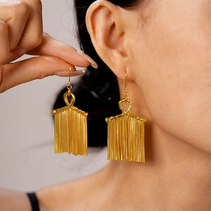 Elegant gold metal tassel earrings with knot design worn by a female model
