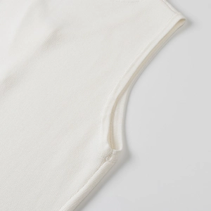 Close-up of the armhole stitching and ribbed texture on the white knitted sleeveless top