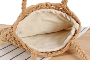 Close-up detail of the cream fabric lining and drawstring closure on the woven tote bag