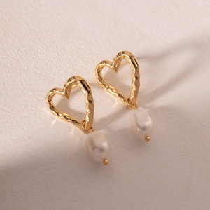 Detailed view of gold hammered hollow heart earrings with elegant pearl drop charms