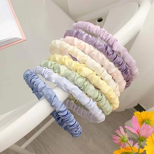 Detail showing various pleated satin headbands in a range of bright pastel colors