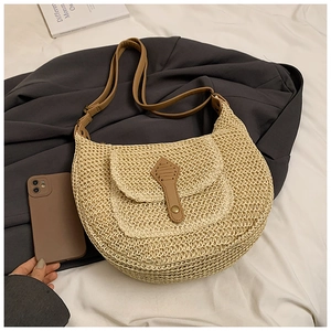 Detailed macro of beige straw hobo bag with brown faux leather pocket and metal snap