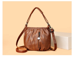 Close-up of brown pleated PU leather handbag with adjustable strap and metal zipper