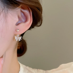 Close-up of a silver bow earring with sparkling cubic zirconia on a model's ear