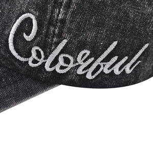 Macro view of white Colorful cursive embroidery on washed black denim baseball cap