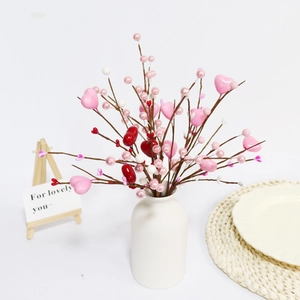 Détail de baies en forme de cœur et perles dans un vase en céramique blanche déco