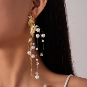 Detail view of golden leaf earrings with pearl tassels and crystal beads on a model