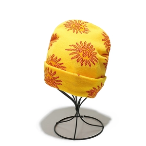 Gros plan du bonnet en tricot jaune vif avec motif soleil sur un support en métal