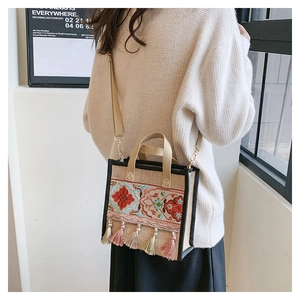 Ethnic embroidered canvas tote bag with colorful tassel charms on a crossbody strap