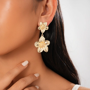 Close-up of model wearing double-layer golden metallic flower earrings with intricate texture
