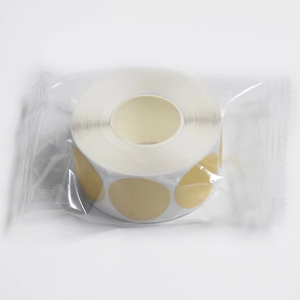 Macro shot of circular gold adhesive kraft paper label roll in transparent packaging