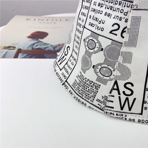 Detailed close-up of white canvas bucket hat with black newspaper print and fine stitching