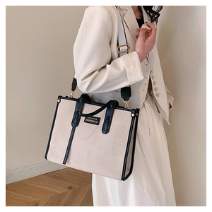 Detail of contrast canvas tote bag featuring premium leather trim and wide shoulder strap