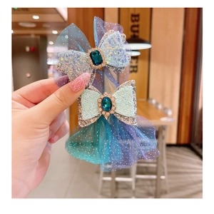 Macro shot of blue gradient mesh bow hair clip with sequins and a sparkling faux sapphire