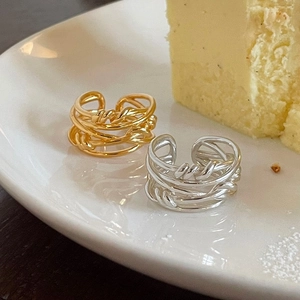 Minimalist 925 sterling silver woven rings in gold and silver finish on ceramic plate
