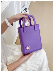 Detail einer lila EVA Jelly Mini Tasche mit süßen Blumen-Ansteckern von Model gehalten