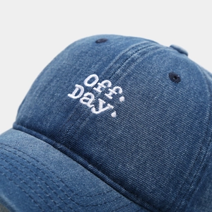 Macro shot of Off. Day. white embroidery on washed dark blue denim baseball cap fabric