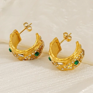 Detail of 18K gold C-shaped earrings featuring hammered texture and green gemstones