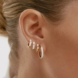 Detail showing white enamel and gold-plated hoops with zircon pavé on female model