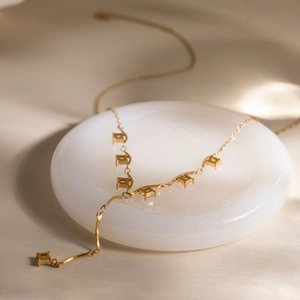 Détail du collier en Y en acier inoxydable doré 18 carats avec breloques carrées en cristal