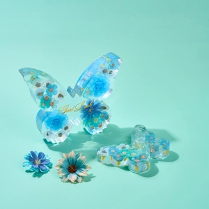 Detail of oversized resin butterfly decor with embedded dried flowers and gold lettering