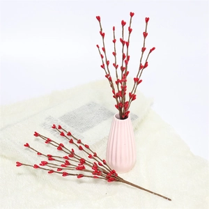 Detail of red artificial berry stems in a pink ceramic vase on soft white texture