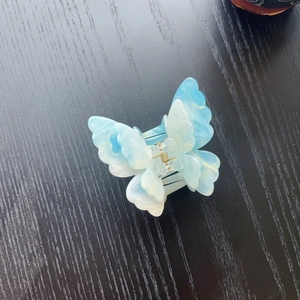 Detailed close-up of blue marble pattern 3D butterfly hair claw with gold spring