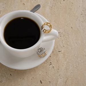 Close-up of 18K gold stainless steel celestial star and moon rings on a coffee cup