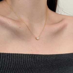 Elegant gold heart pendant necklace with shimmering zircon stones on a female neck