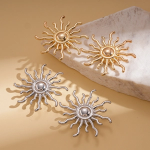Detailed view of gold and silver sunburst stud earrings on white natural stones