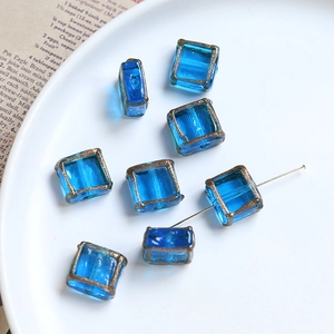 Macro shot of blue square glass beads with gold trim for DIY jewelry making