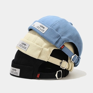 Close-up of three stacked canvas dockers hats in blue, beige and black with metal buckle