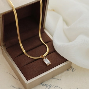 Close-up of golden snake chain necklace with rectangular emerald green stone in a gift box