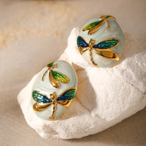 Macro shot of gold-plated dragonfly earrings with marbled enamel and gradient wings