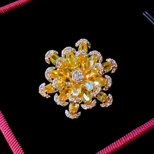 Detail of a floral gold brooch with emerald cut yellow gems and micro-set cubic zirconia