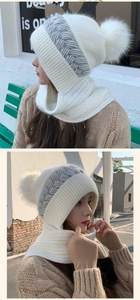 Detail of white knitted hooded scarf with gray cable pattern and plush pom-poms