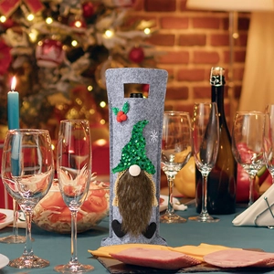 Detail of gray felt Christmas gnome wine bottle cover with sequins in a cozy dinner setting